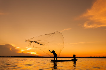 Silhouette,Two fishermen using nets for fishing,sun background 