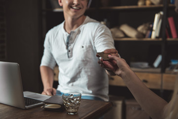 Portrait of stylish man paying with credit card in coffee shop