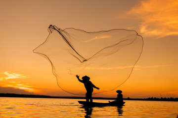 Silhouette,Two fishermen using nets for fishing,sun background 