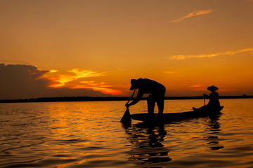 Silhouette,Two fishermen using nets for fishing,sun background 