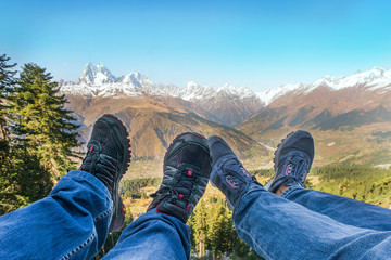 Male and female legs in sneakers and jeans on the background of mountains