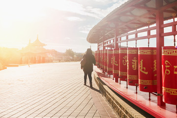 Woman near red Buddhist drums in the sunlight