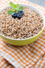 Buckwheat porridge in a bowl with mint leaves and blueberries.