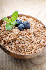 Buckwheat porridge in a bowl with mint leaves and blueberries.