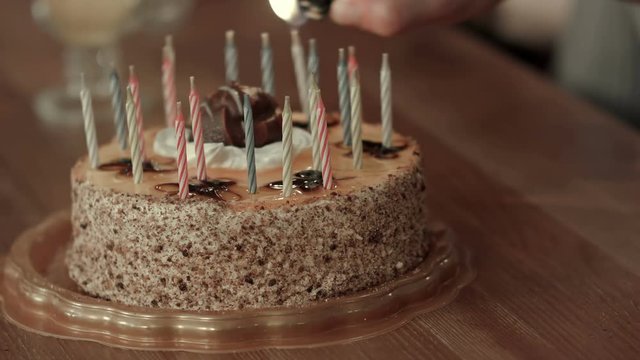 Male hand lighting candles in birthday cake