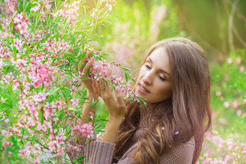 Portrait of young girl sniffs a blooming pink bush