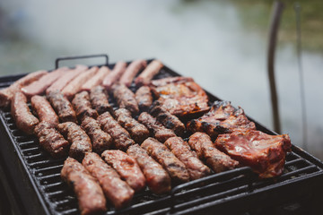 Different type of meats cooked outside, on a hot grill barbecue.
