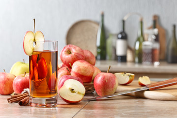Glass of apple juice and ripe pink apples on a kitchen table