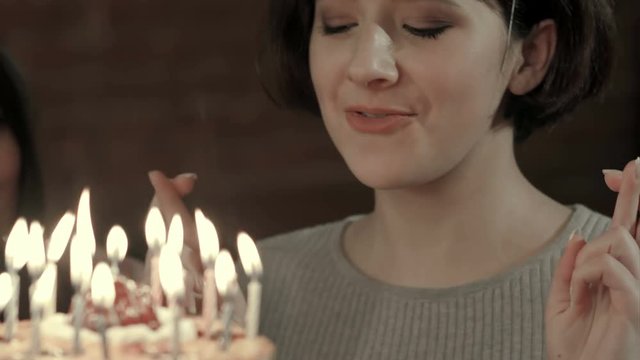 Young attractive girl is about to make a wish and blow all candles