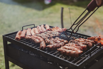 Different type of meats cooked outside, on a hot grill barbecue.