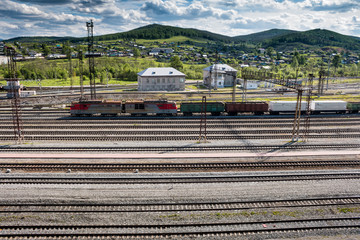 The freight train passes through the railway station in the village