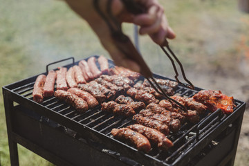 Different type of meats cooked outside, on a hot grill barbecue.