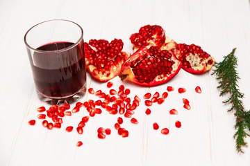 Piece of a cut pomegranate near a glass with pomegranate juice