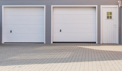Doppelgarage mit weißen Toren und weißer Tür