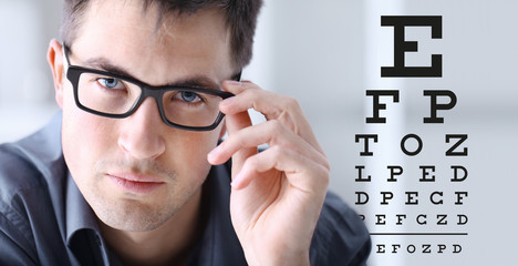 male face with spectacles on eyesight test chart background, eye examination ophthalmology concept