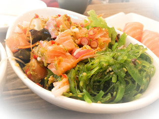 Spicy salmon salad wite sliced seaweed. Contemporary food on a table.