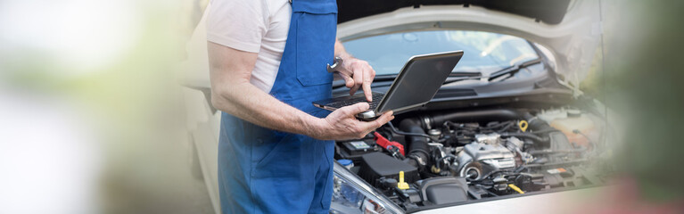 Fototapeta na wymiar Mechanic using laptop for checking car engine