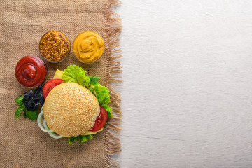 Hamburger with cheese, meat and green onions on Wooden background. Top view. Free space.