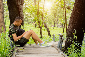 A man happy playing smartphone and  enjoying the fresh air in green forest