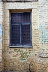 Fototapeta na wymiar Старое окно с битым стеклом на стене кирпичного дома