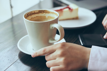 A mug of coffee, a mug is standing on a saucer, a woman with a phone