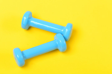 Dumbbells in blue color isolated on bright yellow background