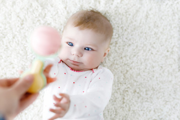 Cute baby girl playing with colorful pastel vintage rattle toy