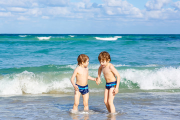 Fototapeta na wymiar Two kid boys running on ocean beach in Florida