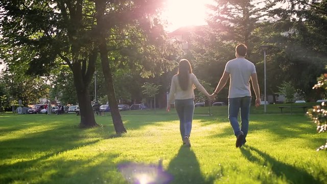 Lovely couple walking together on sunny day holding their hands at park 