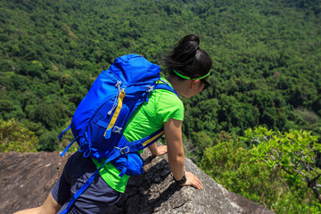 successful woman hiker lying on mountain cliff looking down