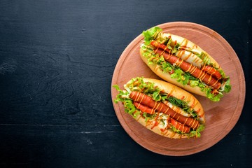 Hot dog with grilled sausage, mustard and ketchup, onions and greens on Wooden background. Top view. Free space.