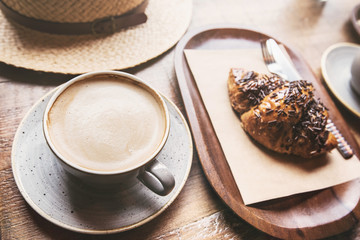 Breakfast, cup of coffee and fresh croissant on a table in a coffee shop