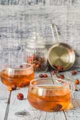 Tea from dry rose hips. Freshly prepared tea from dry rose hips in transparent glass mugs on a gray wooden background.