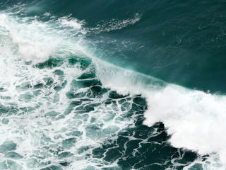 Fototapeta na wymiar A falling big wave with deep blue color details and white foam on caps
