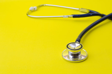 stethoscope on yellow background, heart health care and medical technology concept, selective focus, copy space