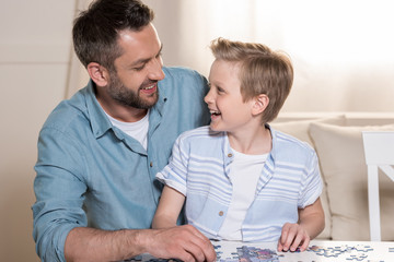 man playing puzzle with son at home