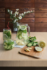 Fresh cold water with lemon, cucumber, ginger, mint and ice in a pitcher and glass on a tray