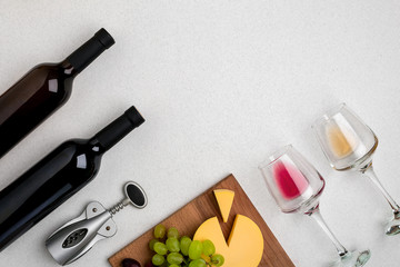 Two glasses of white and red wine, cheese and grapes. Top view