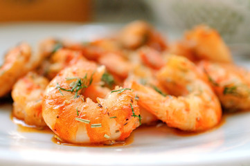 Fried tiger prawns with herbs and spices on a white plate.