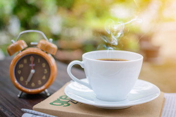 coffee cup clock and news paper on old wooden table nature background