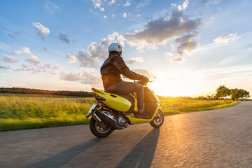 Motorbiker riding on empty road with sunset sky - obrazy, fototapety, plakaty