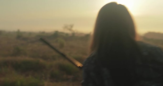 Hunting girl walks through foggy field at sunrise