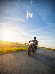 Dark motorbiker riding high power motorbike in sunset