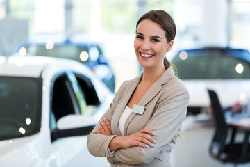 Confident young car dealer standing in showroom
