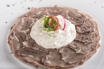 Beef carpaccio with mayonnaise, decorated with herbs, placed on white plate, light background, isolated