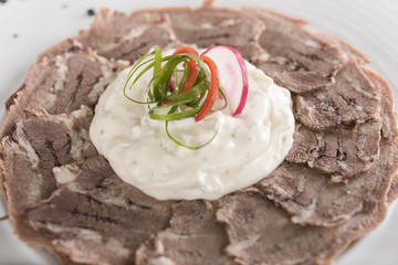 Beef carpaccio with mayonnaise, decorated with herbs, placed on white plate, light background, isolated