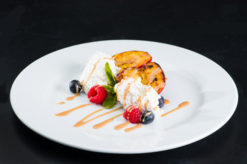 Restaurant dessert for menu. Vanilla ice cream with fruits and caramel syrup on a dark background