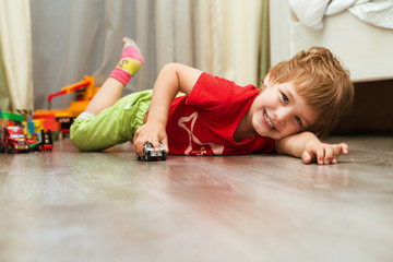 little boy plays with toy car at home