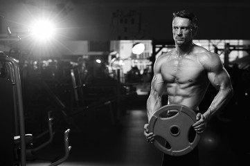 Fototapeta na wymiar Male adult bodybuilder working out with weight