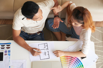 Portrait of young Asian family discussing floor plans and design of new house , above view